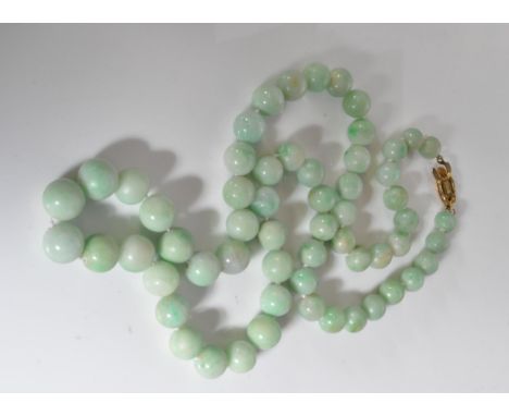 A vintage 20th Century pale green jade beaded necklace constructed of round graduating beads, knotted between each on a gilt 