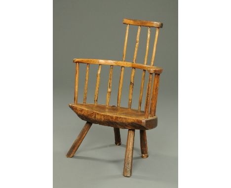 An antique Welsh primitive comb back elbow chair, with bowed top rail with four spindles supporting, solid seat and raised on