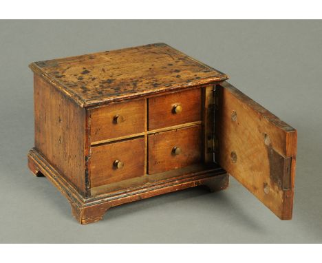 A small early 18th century mahogany table top spice cupboard, with single door to four drawers and raised on bracket feet.  W