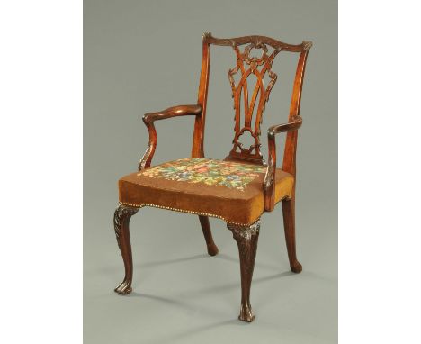 A 19th century Chippendale style elbow chair, with yoke shaped top rail, carved splat back, shaped arms and stuffover seat up