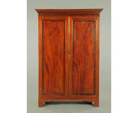 A 19th century mahogany wardrobe, with moulded cornice above a pair of crossbanded and boxwood strung panelled doors opening 