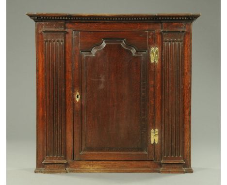 A George III oak hanging cupboard, rectangular, of architectural design, with breakfront top moulding, single panelled door f