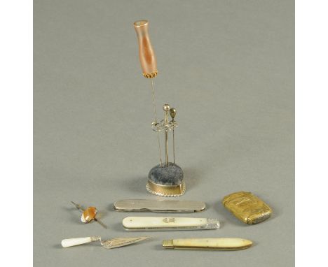 A silver and mother of pearl trowel bookmark, three silver penknives, pin cushion and brass Vesta case.