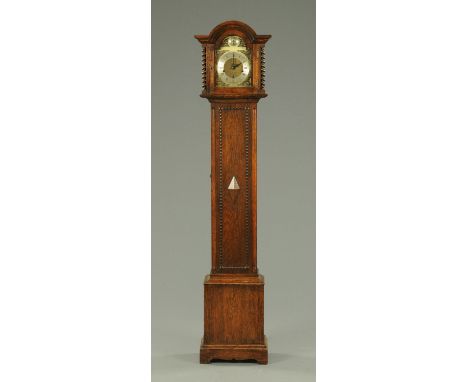 An oak cased grandmother clock, circa 1930, with three-train spring driven movement and with diamond lozenge to the trunk doo