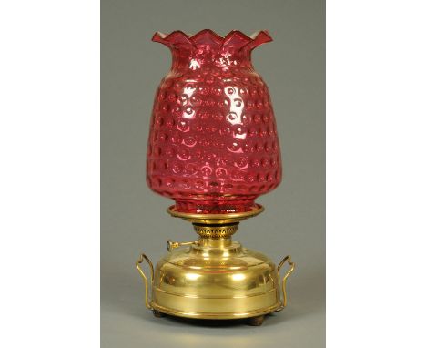 An oil lamp, with cranberry glass shade and brass reservoir.  Height  48 cm.   CONDITION REPORT:  The shade has a number of c