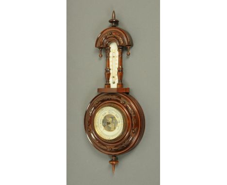 An early 20th century walnut aneroid barometer with mercury thermometer, in carved case.  Height 46.5 cm.