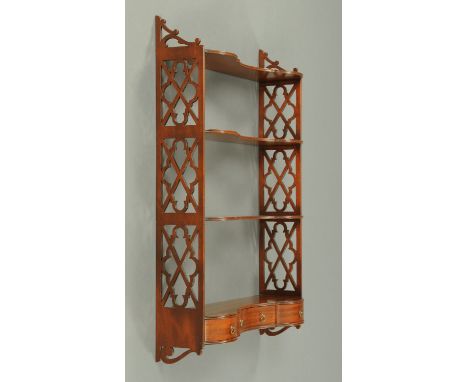 An Edwardian mahogany wall mounting shelf unit, four serpentine tiers and fitted with a series of drawers to the base.  Width