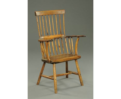 An antique Welsh primitive comb back elbow chair, with bowed top rail to rectangular back with spindled supports, solid seat 