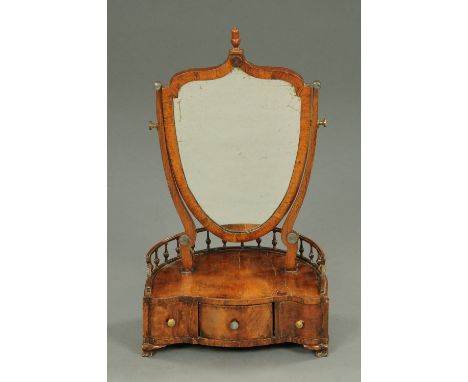 A George III walnut shield shape dressing table mirror, the base fitted with a central drawer, two sliding doors to a further