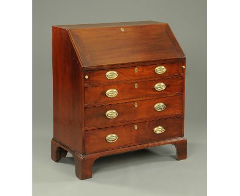 A George III mahogany bureau, with slope front to fitted interior and four frieze drawers with brass drop handles and oval ba