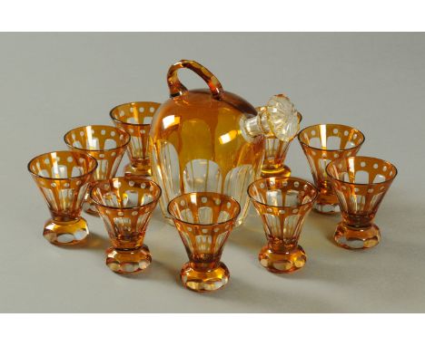 An Edwardian amber glass overlay flask, with nine accompanying glasses each with weighted stem.  