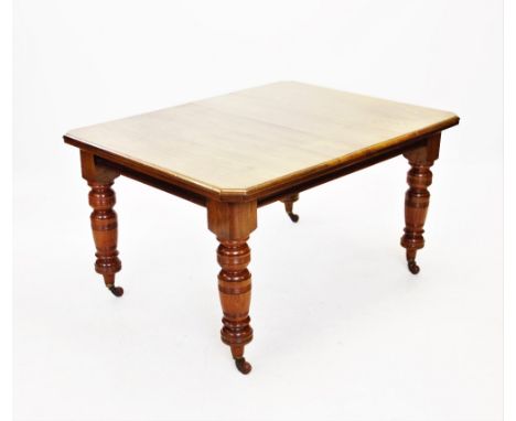 An Edwardian walnut extending dining table, with one extra leaf, the rectangular moulded top with canted corners, raised upon