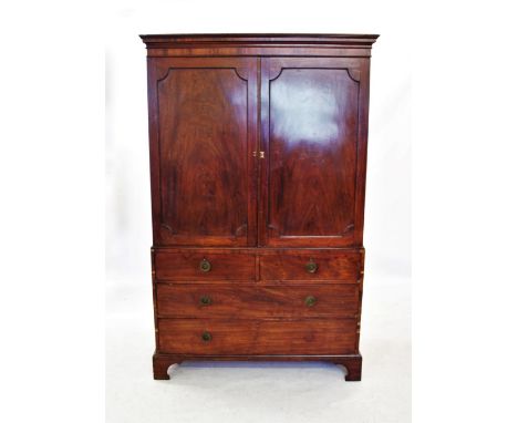 An early 19th century mahogany linen press, the moulded cornice above a pair of panelled doors, enclosing three sliding trays