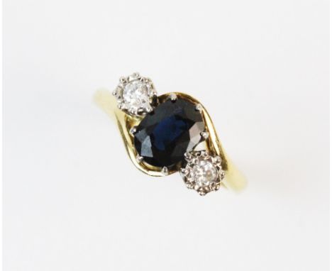 A sapphire and diamond three stone ring, the oval shaped sapphire measuring approx. 8mm x 6mm, flanked by an illusion set bri