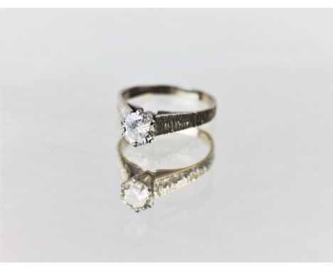 A diamond solitaire ring, the round brilliant cut diamond weighing approx. 1.07 carats, claw set to tapering textured white m