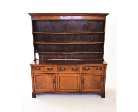 A George III oak high back Welsh dresser, with a moulded cornice above a plain frieze and three enclosed shelves, the base wi