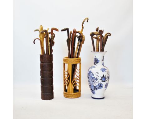 A collection of walking sticks and canes to three stick stands, to include a stick with a dogs mask terminal, knopped example