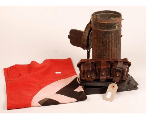 A WWII swastika flag, a leather ammunition pouch, a German gas mask in a metal canister and two machine gun magazines.