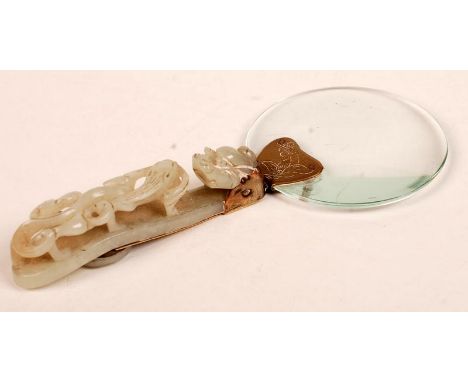 A Chinese carved jade belt hook, now mounted as a magnifying glass.