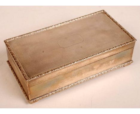 A George V silver cigarette box of rectangular form, the engine turned lid and side panels with raised floral borders, the wh