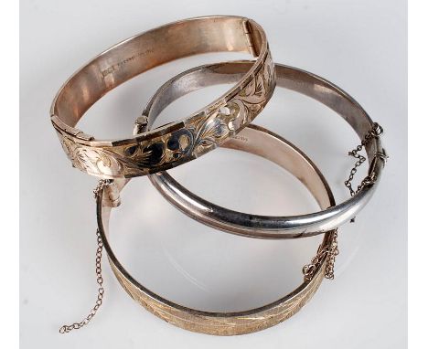 A silver gilt bangle engraved with a band of leaves, by Monomil, together with two similar silver bangles.