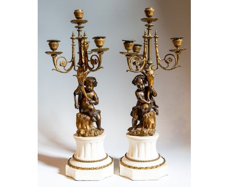 A pair of bronze and ormolu candelabra with white marble bases, each depicting children holding the candelabra, 60cm high (2)