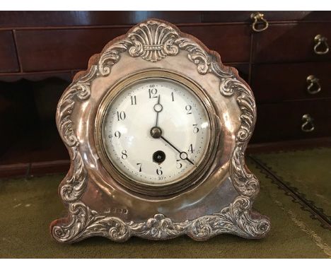 An Edwardian silver faced desk clock, Birmingham 1905, makers mark ‘J.G.’ the silver cast with scrolled decoration on an oak 