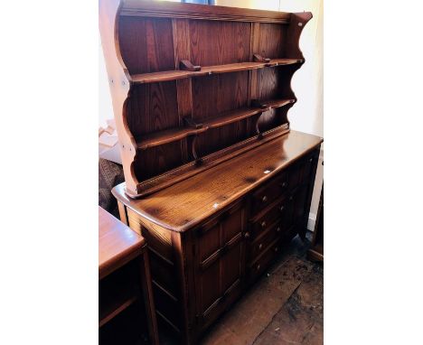An Ercol elm dresser and rack, the rack with two fitted plate shelves, the base section with two cupboard doors and four draw