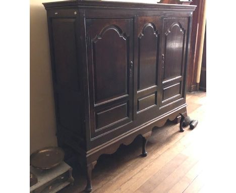 An early 18th Century oak linen press on stand, circa 1710, moulded cornice, above three panel with two doors, original brass