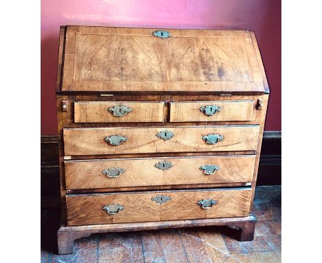 A George II walnut and cross banded bureau, circa 1740, the fall enclosing a fitted interior with arrangement of pigeonholes,