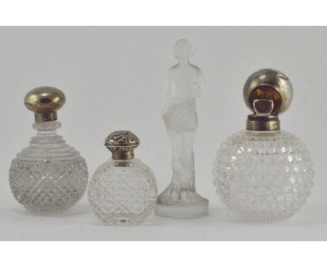 Three early 20th Century silver topped cut glass scent bottles, together with a frosted glass figure of a semi nude lady, reg