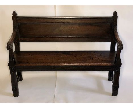 An early 19th century oak settle, circa 1815, spear shape finials on a moulded panel back, floral carved scrolled arms, flora