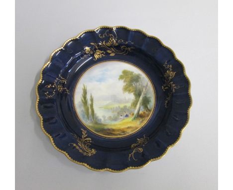 A Royal Worcester Plate with a deep Blue and gilt ground border and scalloped rim. The centre painted with an ‘Italianate’  l