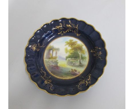A Royal Worcester Plate with a deep Blue and gilt ground border and scalloped rim. The centre painted with an ‘Italianate’  l