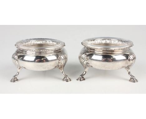 A pair of late Victorian silver circular salts with gadrooned rims, on stylized scallop shell shouldered scroll legs terminat