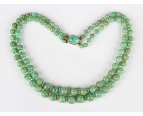 A two row necklace of graduated spherical jade beads, alternating with faceted colourless paste divisions, on a gold and chry