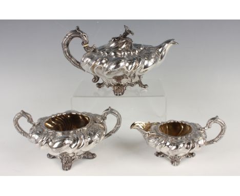 A William IV silver three-piece tea set of squat spiral lobed form, each shoulder chased with flowers and scrolls flanked by 