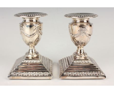 A pair of Elizabeth II silver candlesticks, each with detachable nozzle and ribbon swag decoration, on a stepped square base,