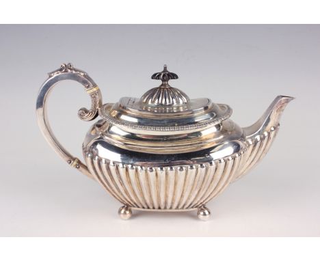 An Edwardian silver half-reeded cushion shaped teapot with foliate capped scroll handle, on ball feet, Sheffield 1909 by Jame