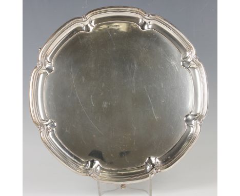 A George V silver circular salver with raised fleur-de-lis and lobed rim, on scroll legs, Sheffield 1933 by Gladwin Ltd, weig