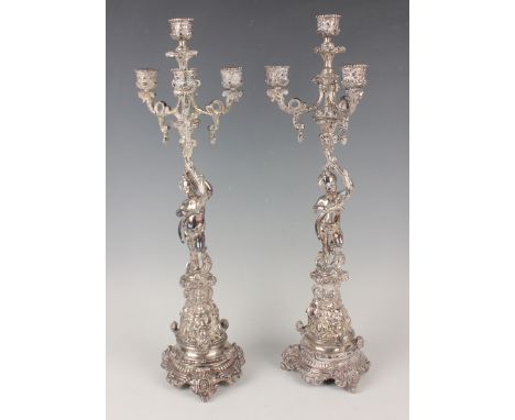 A pair of plated four-light candelabra, each with putto stem and fruiting vine decorated branches, on a scroll moulded trifor