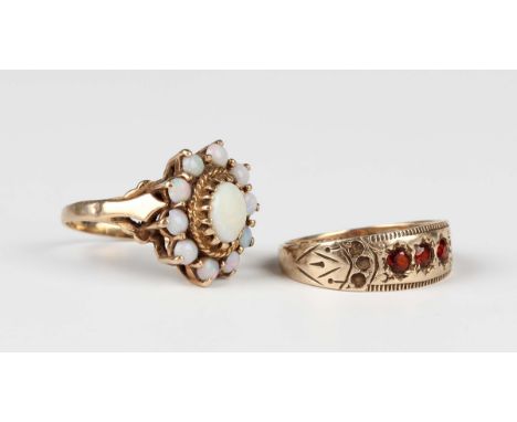 A late Victorian 9ct gold and garnet ring, mounted with a row of three cushion cut garnets between decorated shoulders, Birmi