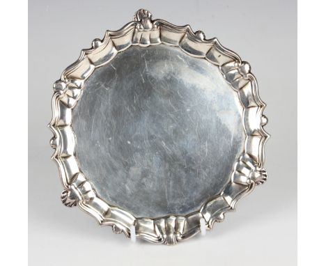 A George II silver card salver with raised scroll and scalloped rim, on three scalloped feet, London 1751 by Edward Feline, w