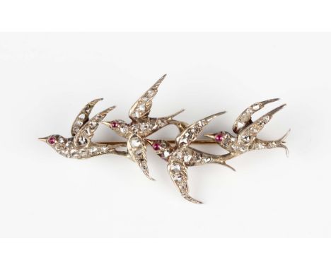 A gold backed and silver set brooch, circa 1900, designed as a row of four swallows in flight, each with a cabochon ruby set 