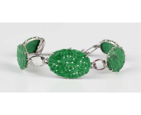 A jade bracelet, mounted with a row of five oval carved and pierced jade panels, on a snap clasp, fitted with a safety chain,