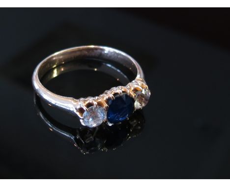 A gold ring with central blue sapphire flanked by white sapphires, unmarked, size M/N, 3.5g