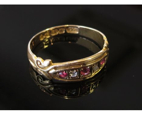 An 18ct gold ruby and sapphire ring with scroll shoulders. 2.2g, size M/N