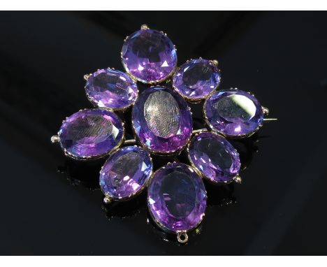 A large amethyst brooch the central oval amethyst framed by eight various sized ovals, unmarked, 25.7g