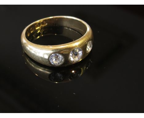 An 18ct gold ring set with three diamonds in rub over setting size O, 5.7g, .65ct total approximately 