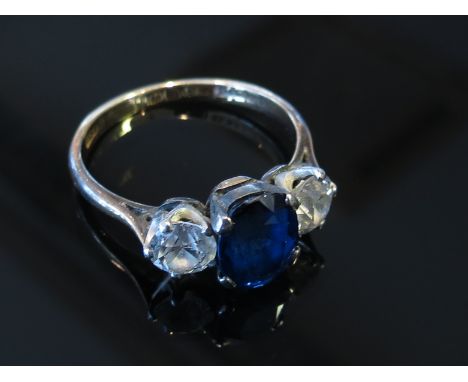 A gold and platinum set sapphire and diamond ring the central blue oval sapphire flanked by .50ct approximately diamonds, siz